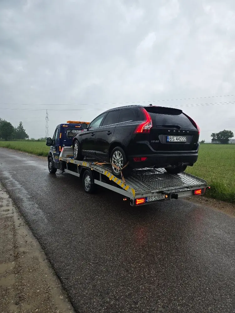Volvo XC60 transportowane na lawecie podczas deszczu.